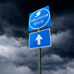 Dark and cloudy skies with an official sign pointing to the hurricane evacuation route.